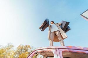 une jeune femme est debout dans une voiture avec des sacs dans les mains photo