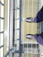 debout portant des chaussures de sécurité noires sur le pont piétonnier photo