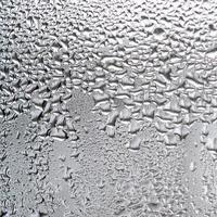 texture d'une goutte de pluie sur un fond transparent en verre humide. tonique en couleur grise photo