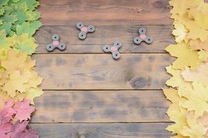 plusieurs fileuses parmi les nombreuses feuilles d'automne tombées jaunissantes sur la surface de fond de planches en bois naturel de couleur marron foncé photo