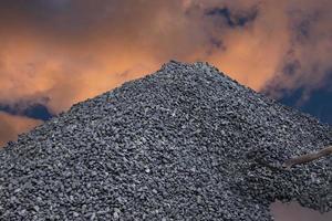 un tas de charbon, une montagne de charbon avec une pleine pelle de charbon sur fond de coucher de soleil. crise de l'énergie. photo