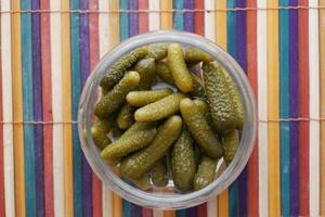 bouteille de concombres marinés, cornichons sur table photo