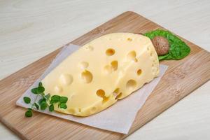 Fromage jaune sur planche de bois et fond de bois photo