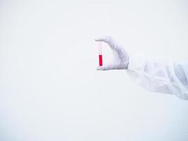 gros plan mains médecin ou scientifique en uniforme de suite epi. équipement de protection individuelle contenant un test de tube sanguin. coronavirus ou covid-19 concept isolé fond blanc photo
