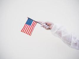 portrait d'un médecin ou d'un scientifique en uniforme de suite epi tenant le drapeau national des états-unis d'amérique. concept covid-19 isolé fond blanc photo