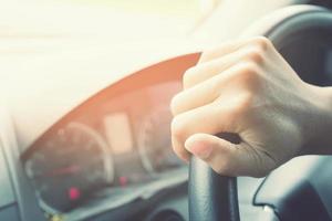 gros plan sur une main tenant le volant jeune femme conduisant une voiture sur la route. voyage de conducteur de voyage. photo