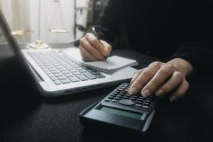 femme entrepreneur utilisant une calculatrice avec un stylo à la main, calculant les dépenses financières au bureau à domicile photo