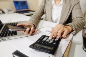 femme entrepreneur utilisant une calculatrice avec un stylo à la main, calculant les dépenses financières au bureau à domicile photo