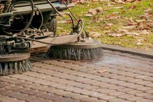 le service municipal effectue des travaux saisonniers dans le parc. la balayeuse ramasse beaucoup de débris. les brosses balayent l'asphalte photo