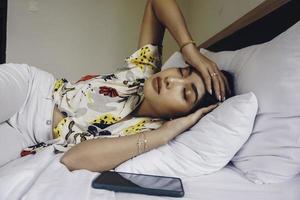 jeune femme séduisante dans la chambre, elle est allongée sur le côté et montre un geste fatigué photo