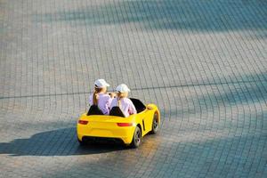 deux petites filles conduisant une petite voiture. véhicule à batterie avec télécommande pour le divertissement des enfants photo