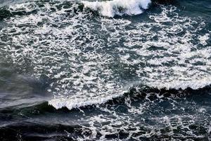 eaux de mer d'un bleu profond éclaboussant de vagues mousseuses, surface d'eau de mer ondulée bleu foncé, embruns marins photo