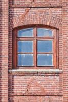 une fenêtre en verre arquée sur le vieux mur de briques rouges photo