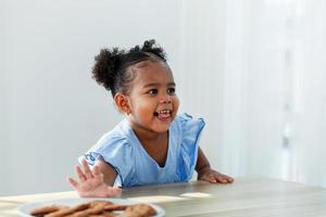 une fille afro-américaine mangeant des biscuits exprime sa peur du silence. pendant que ses parents cuisinent. photo