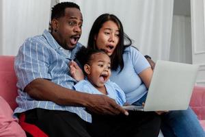 les parents et les filles africains enthousiastes à l'idée d'utiliser la technologie Internet. s'asseoir sur le canapé du salon. photo