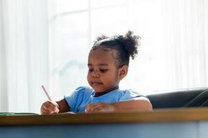 heureux petit étudiant afro-américain mignon. dessin sur le tableau. concept éducatif enfant en pleine croissance photo