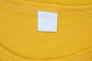 étiquette d'étiquette de vêtement blanc vierge sur nouveau fond de chemise jaune photo