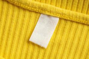 étiquette d'étiquette de vêtement blanc vierge sur nouveau fond de chemise jaune photo