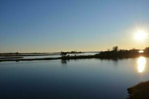 un lac ou une rivière avec des herbes brunes et un rivage photo