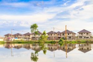 Nouveau bâtiment de maison réflexion avec de l'eau dans le lac sur le site de construction d'un domaine résidentiel avec nuages et ciel bleu photo