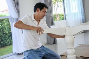 homme asiatique assemblant des meubles de table blancs à la maison photo