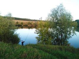 pêcheur à l'extérieur près de l'étang essayant d'attraper un poisson photo