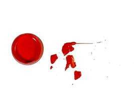 acrylique rouge dans un bocal sur fond blanc. gouttes de peinture sur la table. photo