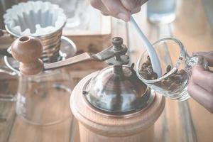 le barista prépare le grain de café avec un moulin à café manuel pour faire du café goutte à goutte. photo