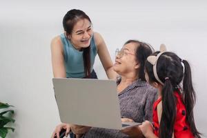 heureux trois générations de femmes s'asseoir se détendre sur le canapé rire en regardant une vidéo amusante sur un ordinateur portable