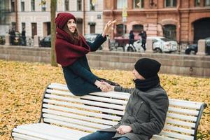 de belles femmes et hommes s'amusent à l'extérieur, s'assoient sur un banc, gardent les mains ensemble, se regardent avec beaucoup d'amour, étant très romantiques et détendus. notion de convivialité photo