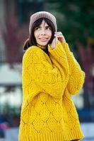 belle brune européenne vêtue d'un pull en laine jaune et d'un chapeau à l'extérieur. la belle fille qui porte des vêtements d'automne épais et élégants par temps frais. photo