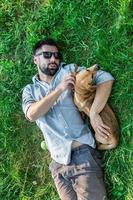 vue de dessus de l'homme et du chien allongé sur l'herbe verte. un homme européen séduisant étreint son chien. photo