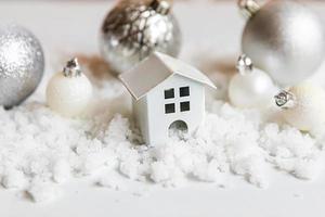 fond abstrait de Noël de l'avent. maison modèle de jouet et décorations d'hiver ornements jouets et balles sur fond de neige. noël en famille à la maison. concept de temps de joyeux noël. photo