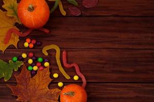 bonbons traditionnels d'halloween. citrouilles, feuilles d'automne et bonbons sur fond en bois. photo