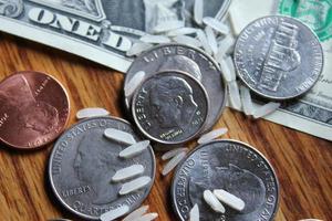 des pièces d'un dollar et des billets d'un dollar sont éparpillés sur une table en bois avec des grains de riz. photo