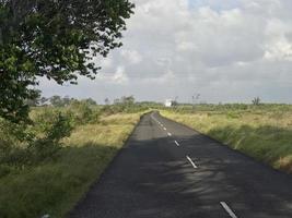 la vue sur l'autoroute avec une belle herbe qui s'étend le long du bord de la route et des nuages blancs couvrant photo