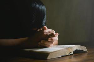 main de personne de prière sur fond noir. une femme catholique chrétienne prie Dieu dans le noir à l'église. fille croit et foi en jésus christ. la religion du christ et le christianisme adorent ou prient le concept. photo