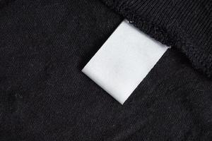 étiquette de vêtements de soin de lessive blanche vierge sur la texture du tissu noir photo