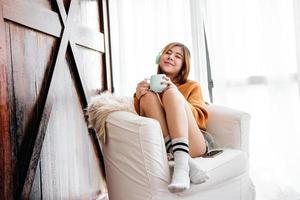 mise au point douce d'une jeune femme heureuse se relaxant par un casque de musique depuis un smartphone sur un canapé dans une maison confortable, mode de vie des gens modernes photo