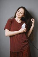 jeune femme séchant ses longs cheveux avec un sèche-cheveux photo