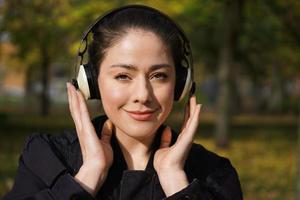 jeune femme écoutant de la musique avec des écouteurs sans fil à l'extérieur photo