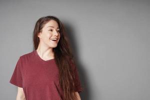 Happy smiling young woman in her 20s with natural make-up and brunette long hair looking to side photo