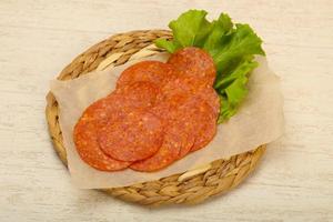 Saucisse au pepperoni sur planche de bois et fond de bois photo