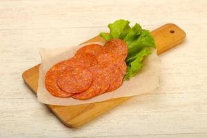 Saucisse au pepperoni sur planche de bois et fond de bois photo