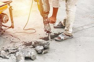 travailleur de la construction à l'aide d'un marteau-piqueur forant une surface en béton photo