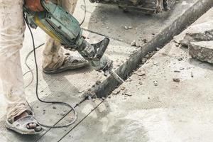 travailleur de la construction à l'aide d'un marteau-piqueur forant une surface en béton photo