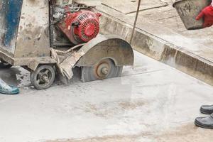 travailleur utilisant une machine à lame de scie diamantée coupant une route en béton sur un chantier de construction photo