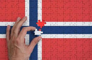 le drapeau de la norvège est représenté sur un puzzle, que la main de l'homme complète pour se plier photo