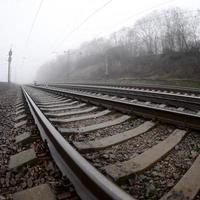 la voie ferrée par un matin brumeux. beaucoup de rails et de traverses vont dans l'horizon brumeux. photo fisheye avec distorsion accrue