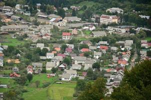 une belle vue sur le village de mezhgorye, région des carpates. beaucoup de bâtiments résidentiels entourés de hautes montagnes forestières et d'une longue rivière photo